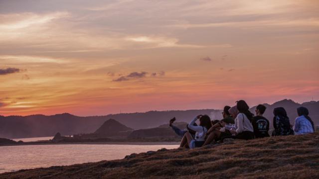 Tourists sit at Merisik Hill during sunset in Lombok island, Indonesia. Photo credit: Asian Development Bank.
