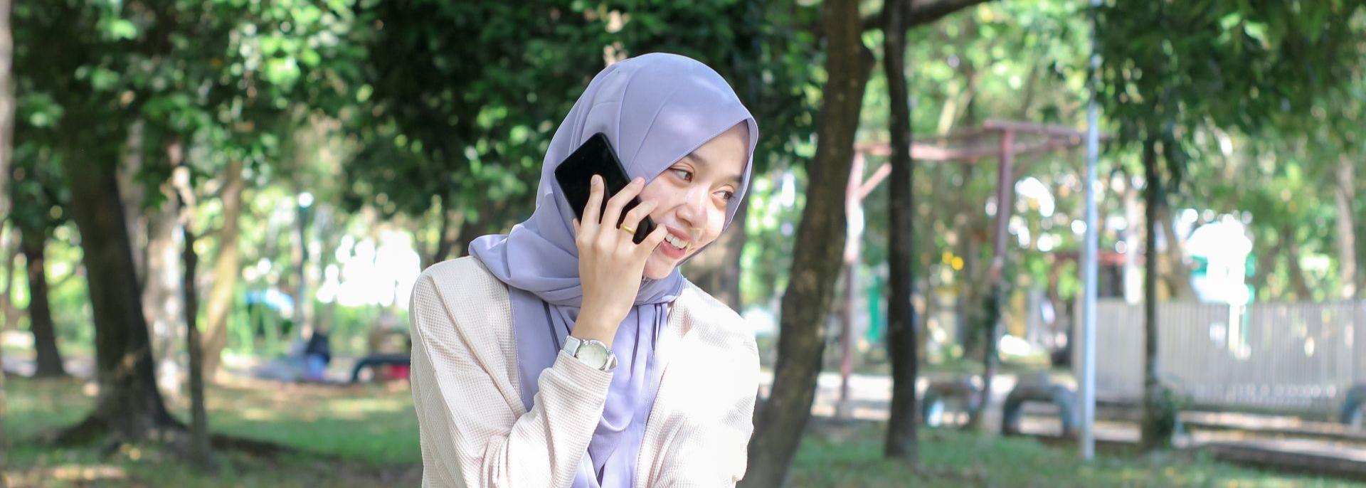 A woman wearing a hijab talks to someone on her mobile phone. Photo credit: iStock/Adennysyahputra.